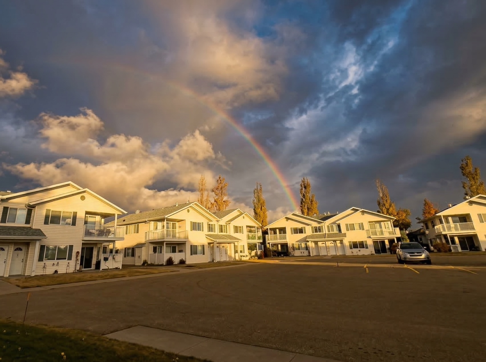Cream-colored Northridge Estates buildings under a dramatic sky with a rainbow arcing over the residential community.